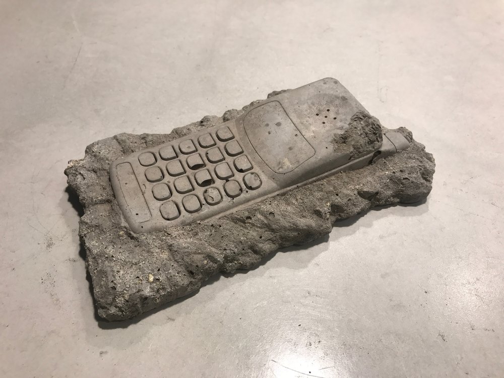 "Fossilized" Nokia push-button cell phone suspended in clay. Artwork by ceramicist Christopher Locke