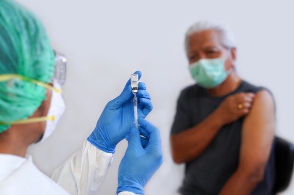 Photo of a healthcare worker holding a syringe, and a patient exposing their arm.